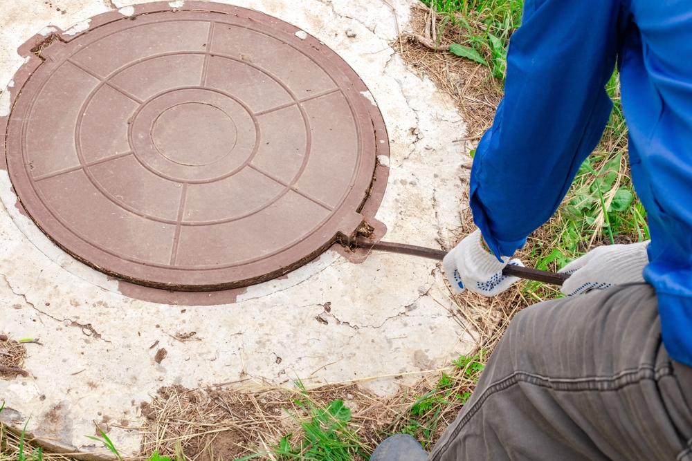 A,plumber,opens,a,manhole,cover,on,a,concrete,well